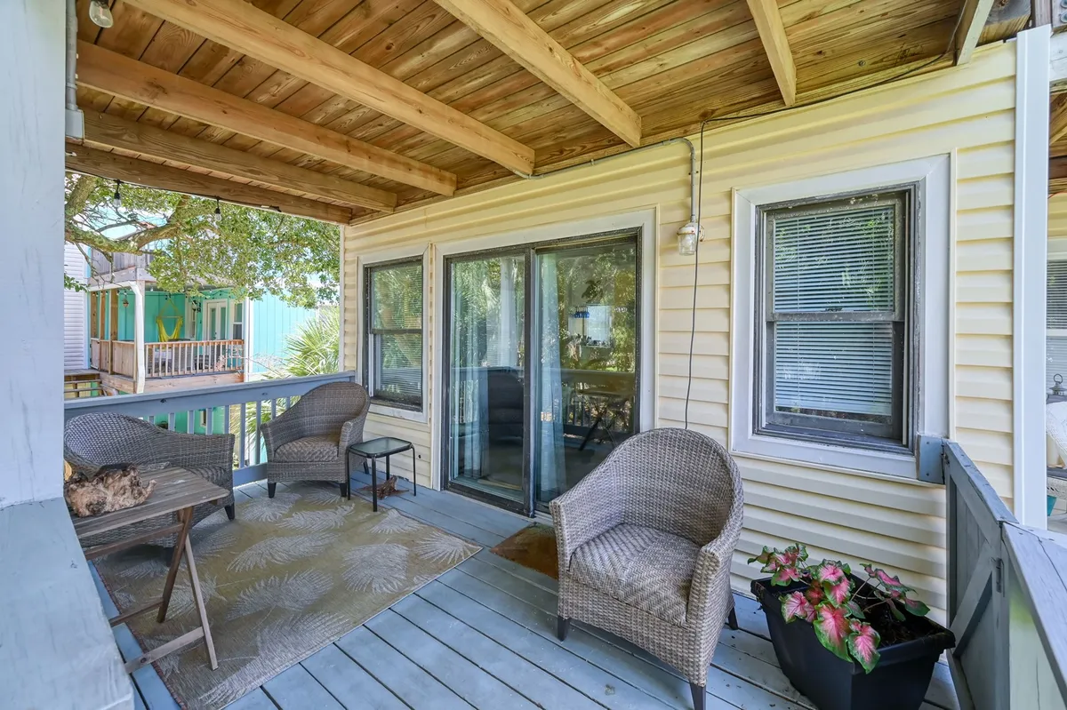 A comfortable exterior sitting area with woven chairs on an outdoor rug, complemented by a potted plant. The seating arrangement is casual and practical, ideal for relaxing after a day at the beach or letting pets enjoy the fresh air with their owners.