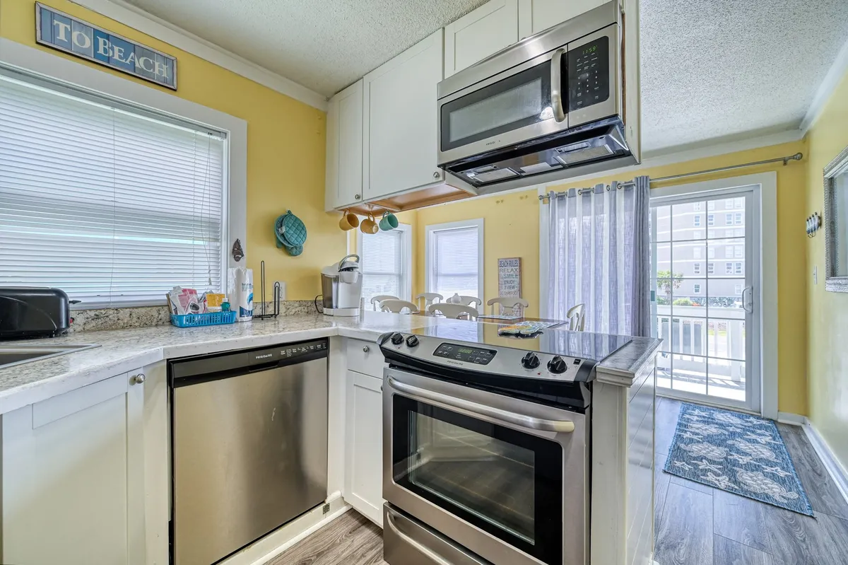 A comfortable, well-lit kitchen and dining area featuring stainless steel appliances, yellow walls, and a window letting in natural light. The setting suggests opportunities for family dinners, group gatherings, or casual meals—ideal for budget-conscious travelers seeking memorable shared experiences.