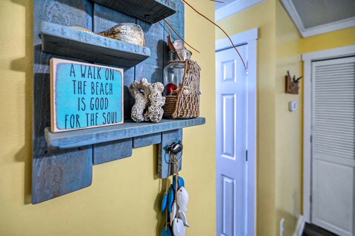 A cheerful, coastal-inspired shelf scene with bright yellow walls, decorative items, and a sign with text. The decor and color scheme are reminiscent of a sunny beach day and evoke the friendly, inviting spirit of Surf City and Topsail Island.
