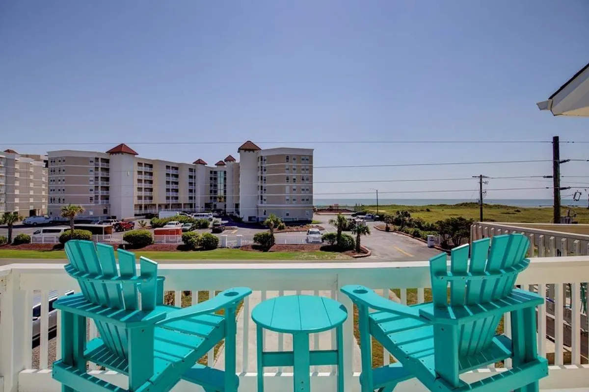 A cheerful exterior seating area featuring turquoise chairs positioned to enjoy views of surrounding buildings and lush greenery. The space suggests opportunities for relaxation and connecting with the outdoors just steps from the family suite.