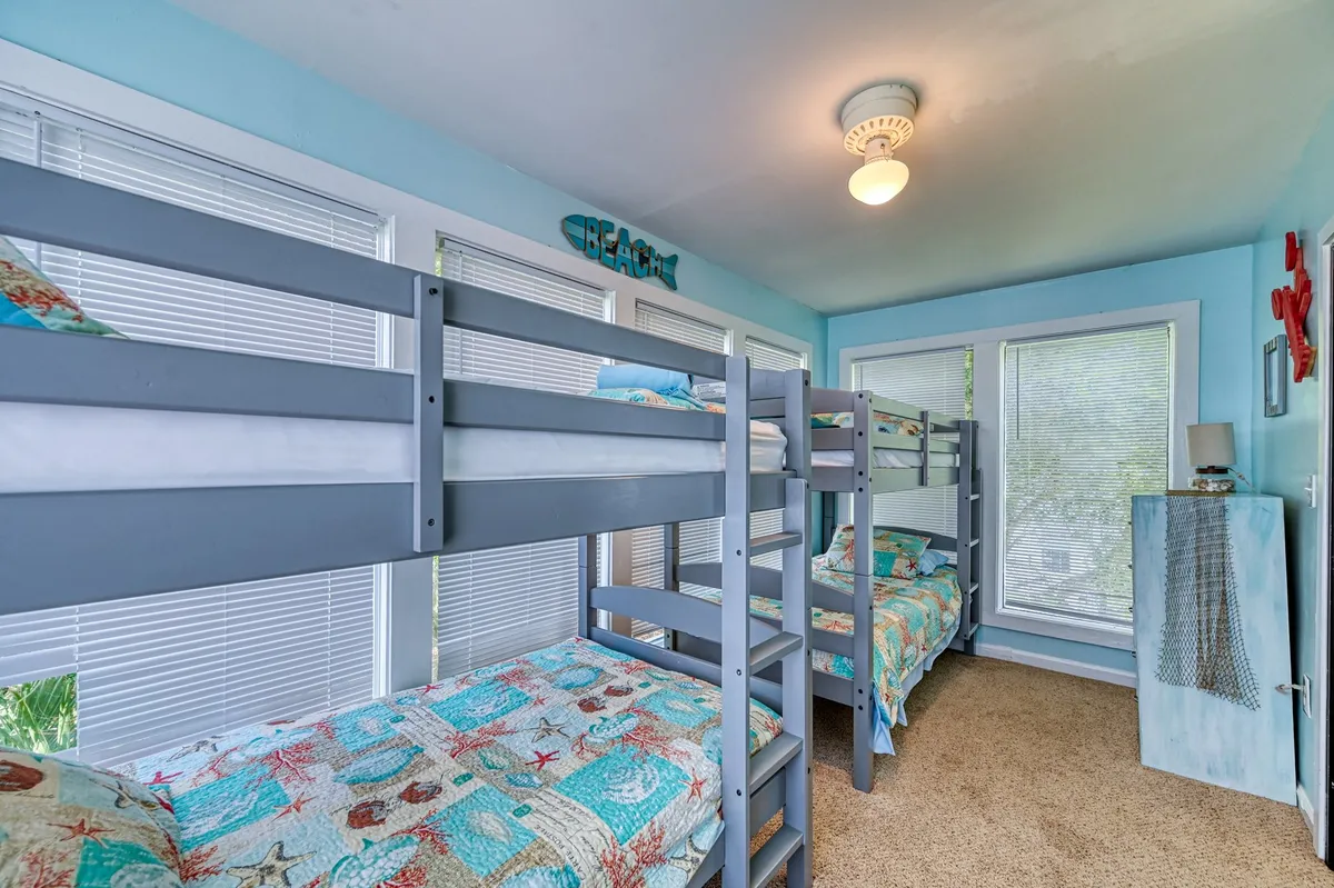 A bright, kid-friendly bedroom with cheerful bunk beds, beach-themed decor, and large windows. The playful design encourages sleepovers and imaginative play, reinforcing the family-friendly appeal.