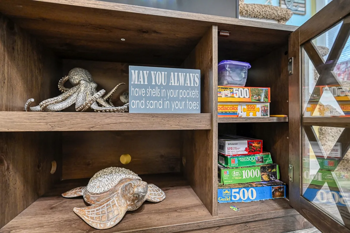 This image features a collection of playful beach-themed decor, including a decorative octopus and turtle sculpture, a sign with a lighthearted beach saying, and puzzle boxes. The arrangement evokes a relaxed, seaside atmosphere and hints at leisure activities and family fun.