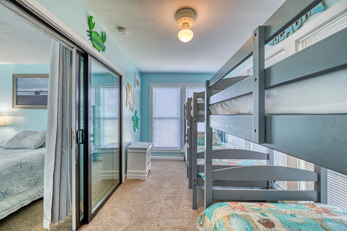 This playful interior scene presents bunk beds with colorful bedding, a modern light fixture, and decorative wall elements. The space feels energetic and inviting, ideal for children or family members to enjoy restful nights or playful bonding.